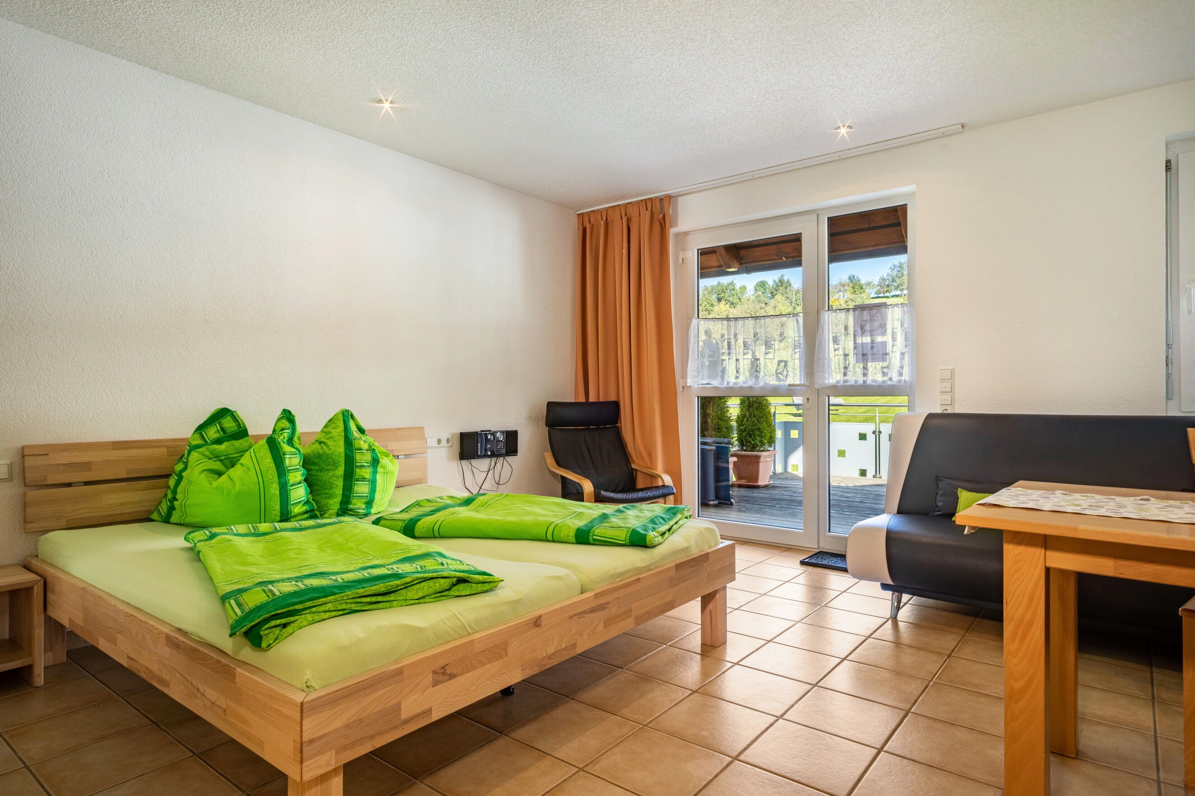 Una habitación con cama, una silla, una mesa y un balcón con vistas.