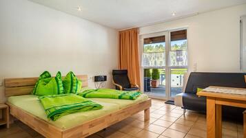 Una habitación con cama, una silla, una mesa y un balcón con vistas.
