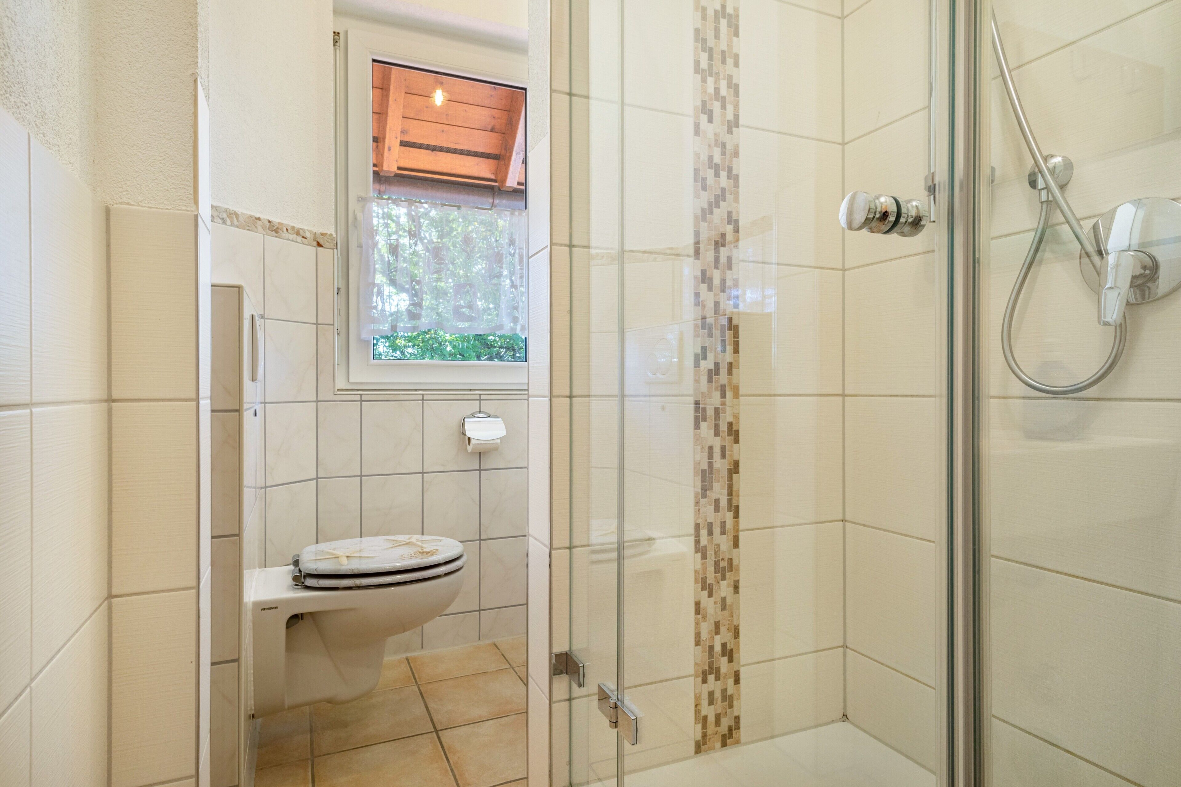Ein Badezimmer mit Toilette, Dusche und Fenster.