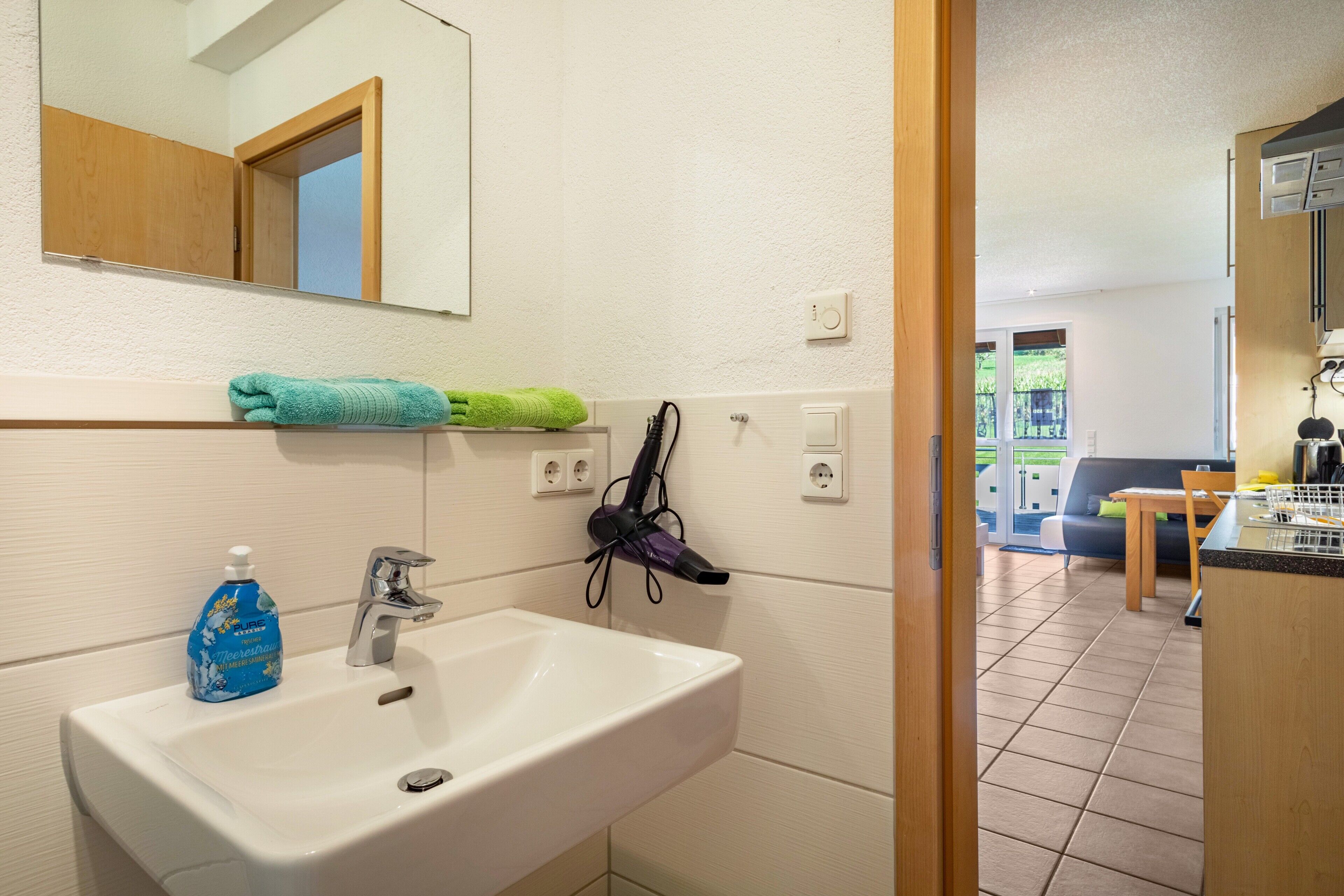 Une salle de bain équipée d’un lavabo, d’un miroir et d’un porte-serviettes.