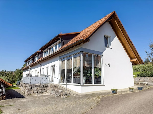 Ein zweigeschossiges Haus mit geneigtem Dach, großen Fenstern und einem Steinfundament.