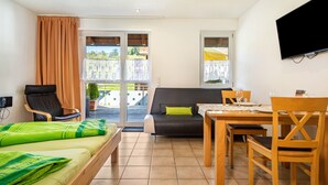 Une pièce comprenant un lit, un canapé, une table à manger avec des chaises, un téléviseur fixé au mur et un balcon avec vue.