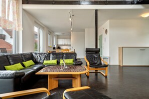 Un salon moderne avec un canapé en cuir noir, des coussins verts, une table basse en bois et un fauteuil en cuir noir.