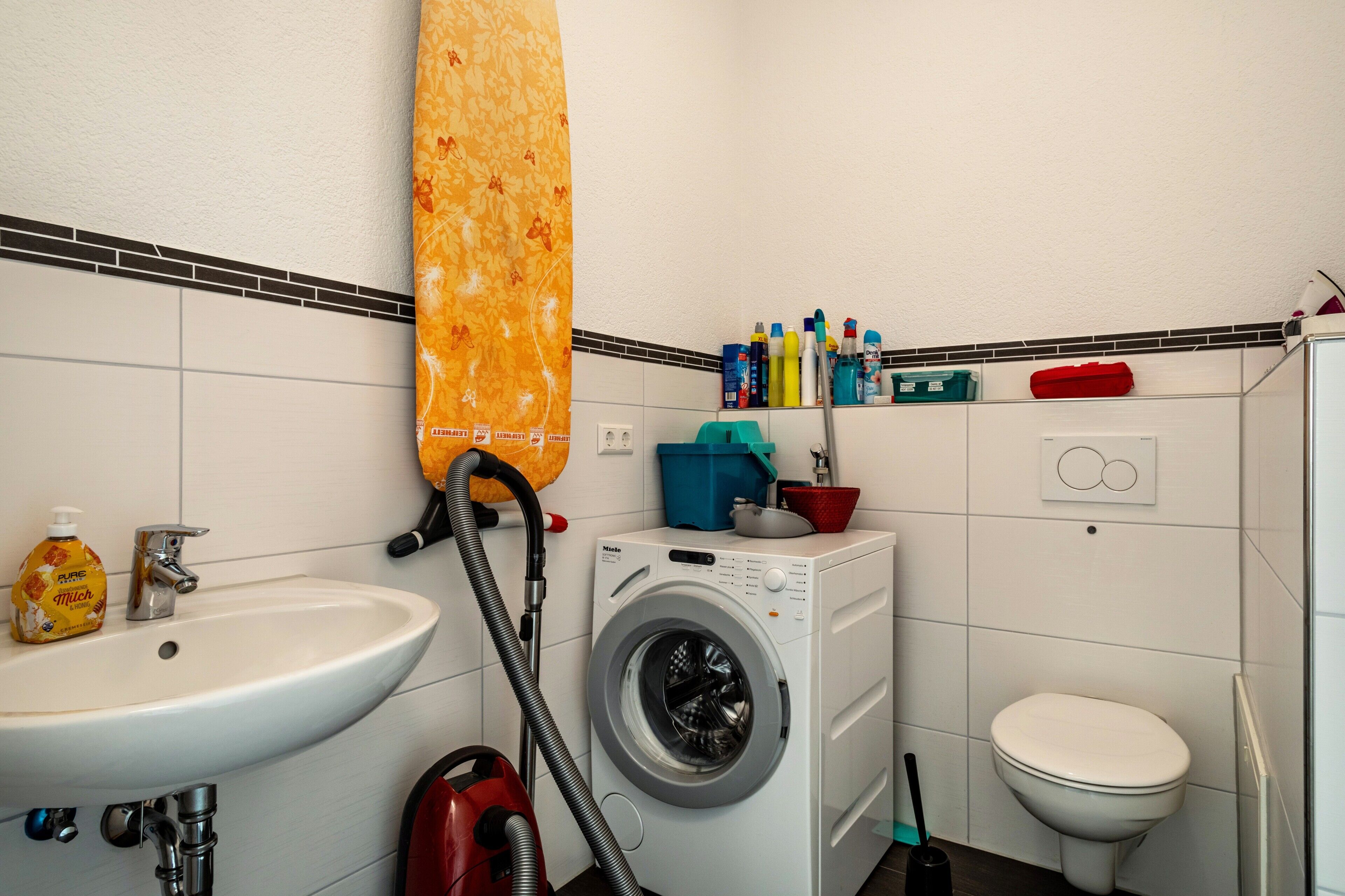 Un bagno funzionale con lavandino, lavatrice, water e zona doccia.