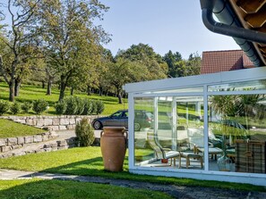Une structure moderne en verre, avec un mur en pierre et une voiture garée à l’extérieur.