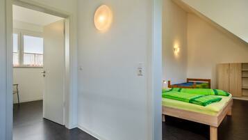 Ein Schlafzimmer mit Bett, Fenster und einer Tür zu einem anderen Raum.