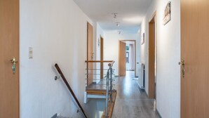 Un pasillo con puertas de madera, una escalera metálica y un radiador.
