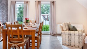 Un área de comedor con una mesa y sillas de madera, un sofá y vistas a zonas verdes.