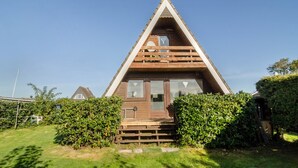 Una cabaña de madera con techo triangular, un porche delantero y un ventanal pequeño.