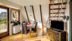 Un interior moderno con comedor, televisor y techo estilo loft.