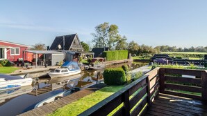 Una propiedad a orillas de un canal con un muelle para barcos, un edificio rojo y una terraza de madera.