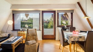 Un interior moderno con zona de comedor, un sofá, una mesita y vistas a través de una puerta.