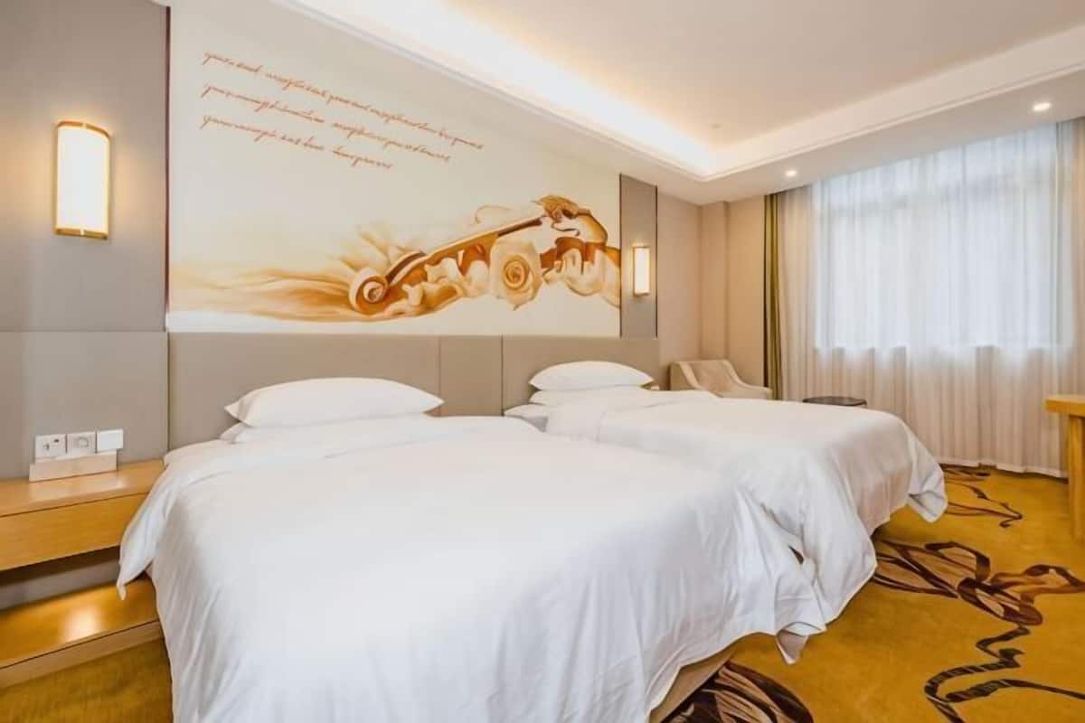 Una habitación de hotel con dos camas, una obra de arte en la pared y un amplio ventanal con cortinas.