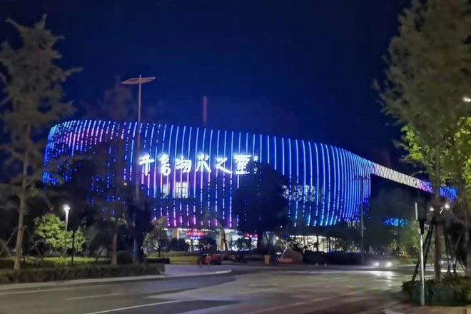 A large building with illuminated signage and a curved structure.