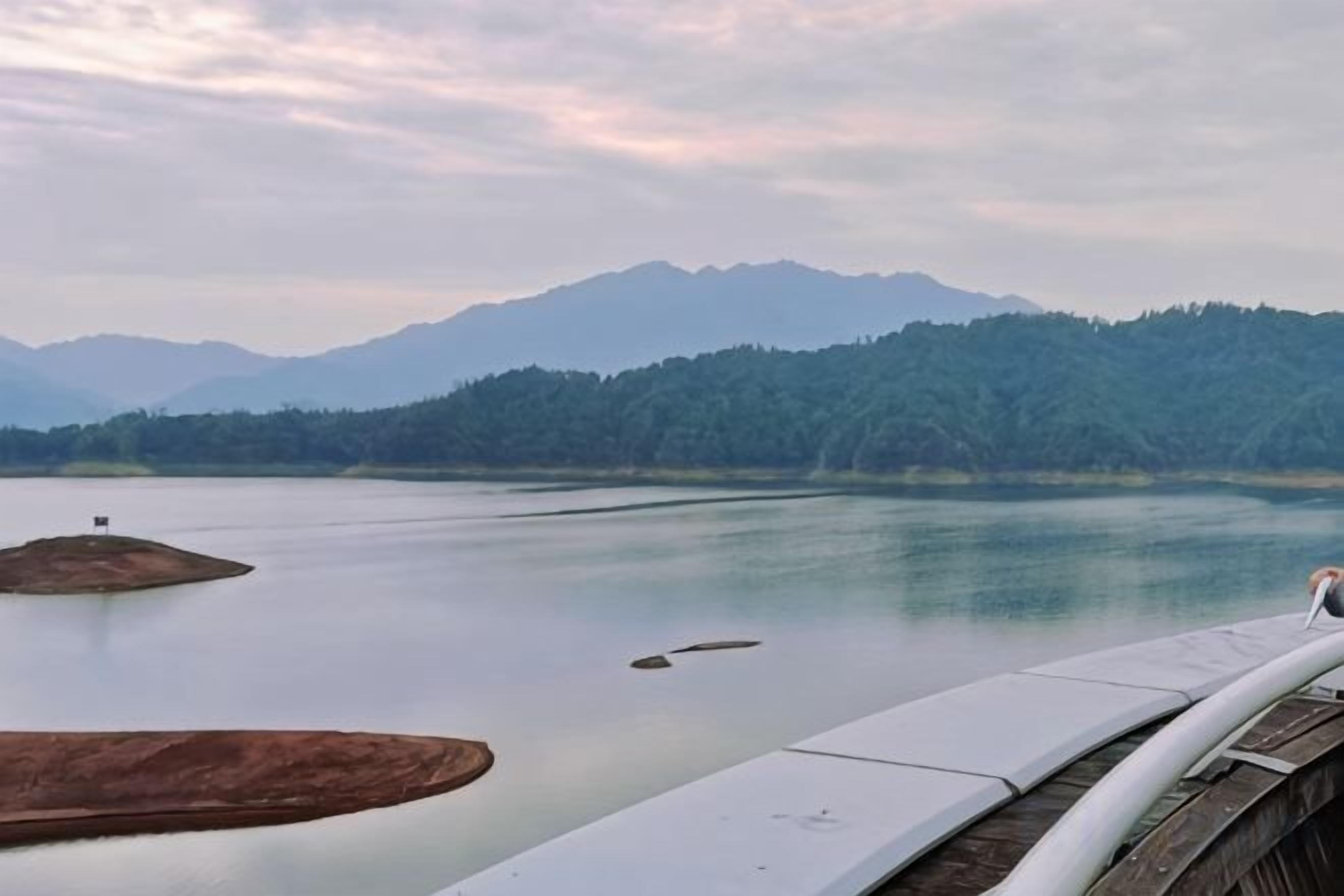 A calm lake with mountains in the background and a bridge in the foreground.