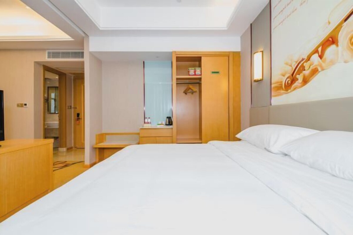 Una habitación de hotel con cama, escritorio, armario y espejo.