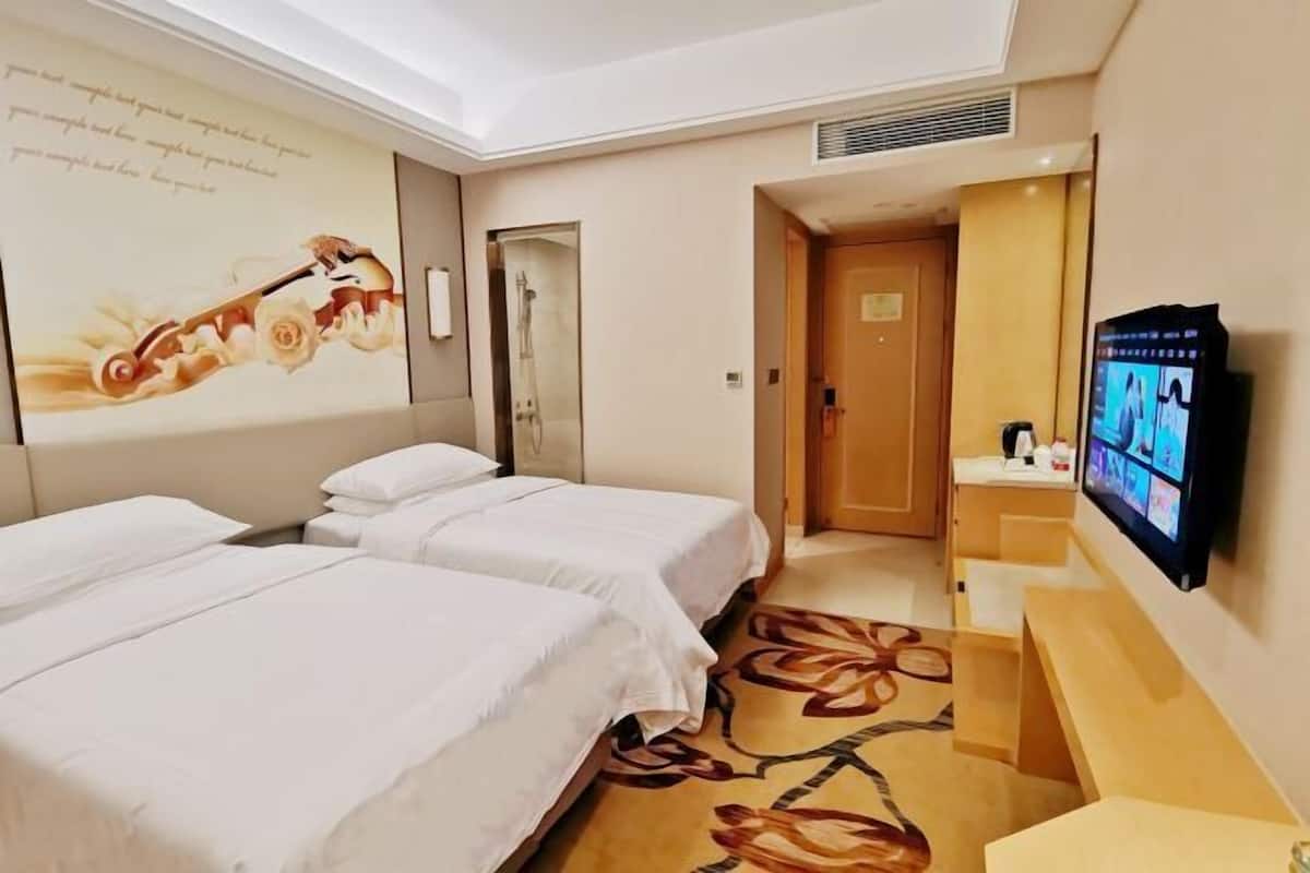 Habitación de hotel con dos camas, televisión, baño y un adorno en la pared.