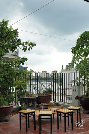 A terrace with potted plants, a grill, and outdoor seating. - Pegasy Apartments & Travel (Hanoi)