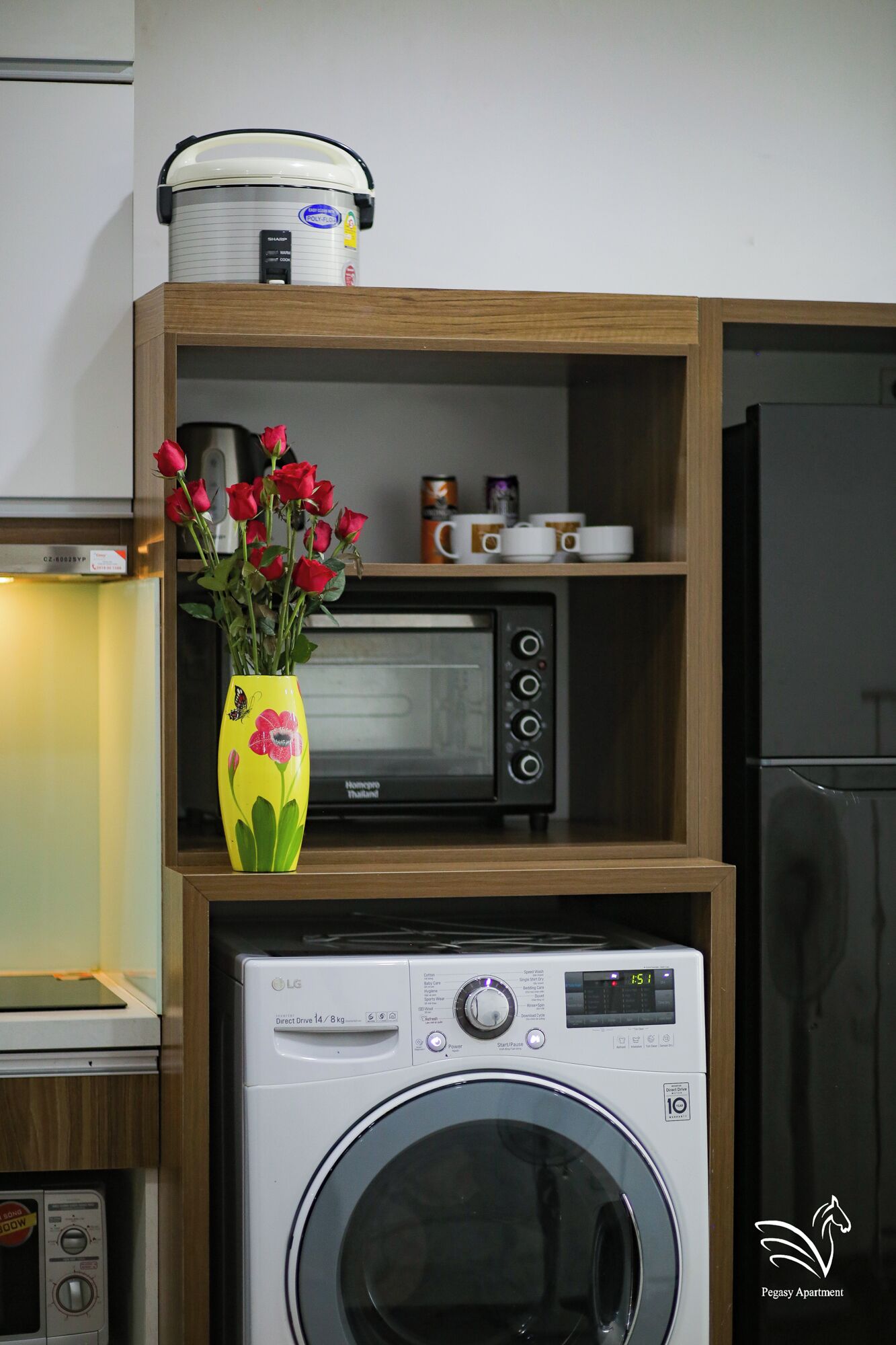 A kitchen with a microwave, a rice cooker, a toaster oven, and a washing machine.