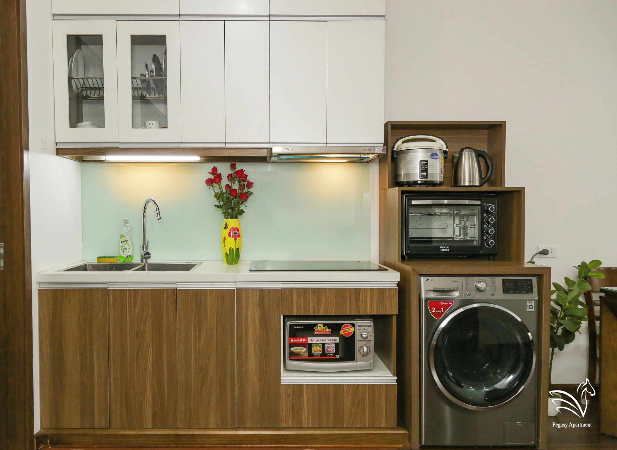 A compact kitchen with a microwave, toaster, and washing machine.