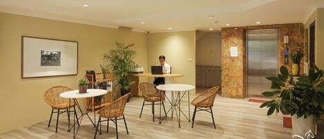 A modern office space with a desk, chairs, a laptop, and a framed picture on the wall.