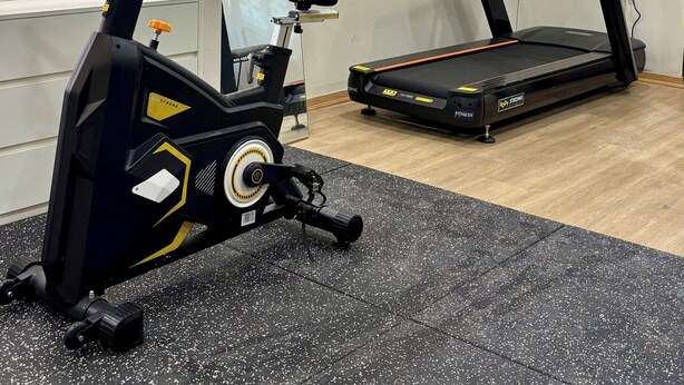 Une salle de sport équipée d’un vélo d’exercice, d’un tapis de course et d’un téléviseur fixé au mur.