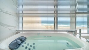 A bathroom with a bathtub, a shower, and a view of the beach through large windows. - Goseong Moneblue Pension (Goseong)