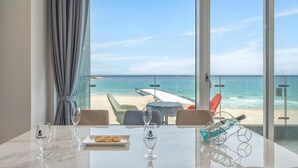 A room with a view of the beach, a table with two glasses and a plate of crackers, and a chair with a patterned tablecloth. - Goseong Moneblue Pension (Goseong)