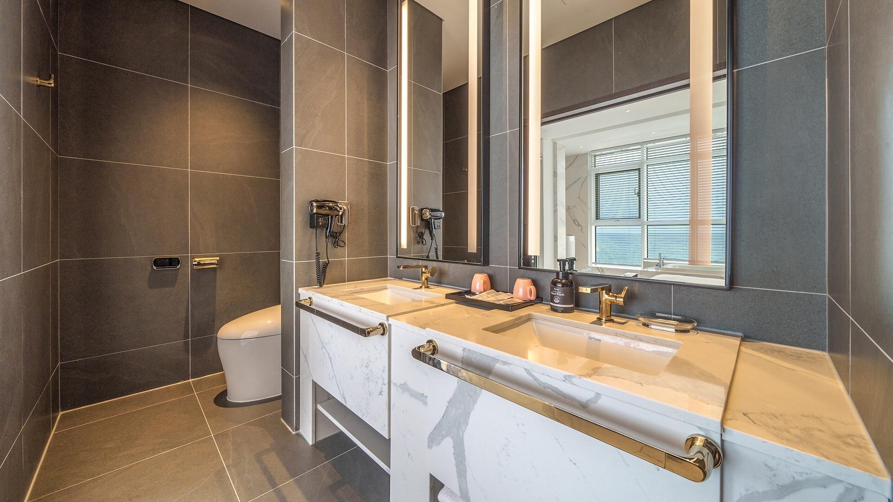 A modern bathroom with a dual sink vanity, a large mirror, and a shower area.