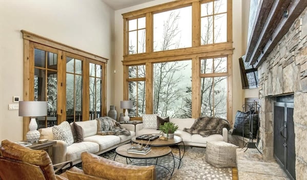 A spacious living room with large windows, a fireplace, and a cozy seating area.