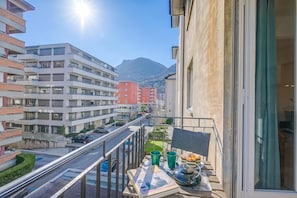 Un balcón con vista a una calle, edificios y una montaña.