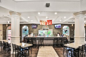 Enjoy a meal at our restaurant, where a central bar area offers a variety of beverages and food, and multiple seating options are available for groups and individuals.