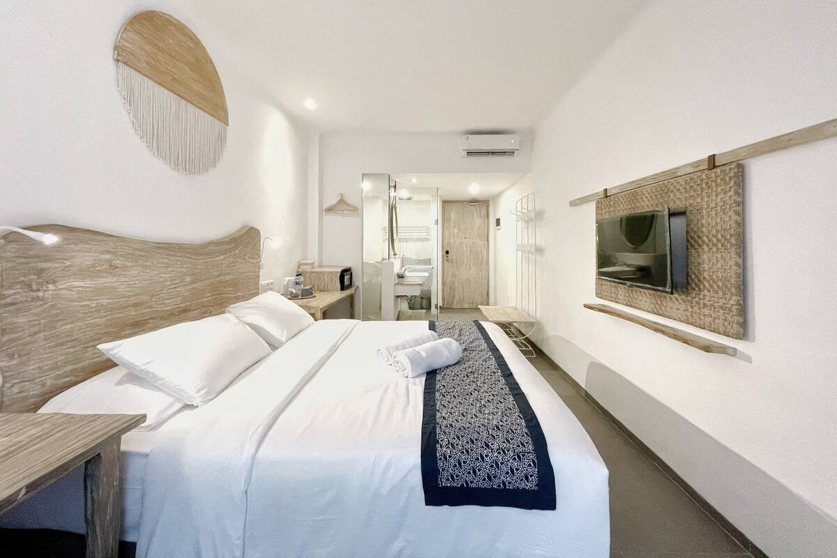 Ein Hotelzimmer mit einem großen Bett, einem Holz-Kopfteil, einem flachbildfernseher an der Wand und einem Spiegel über dem Bett.