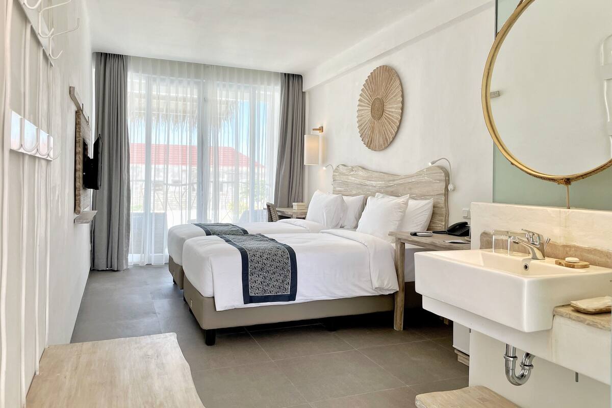 Ein Hotelzimmer mit Bett, Nachttisch und einem Badezimmer mit Waschbecken und Spiegel.