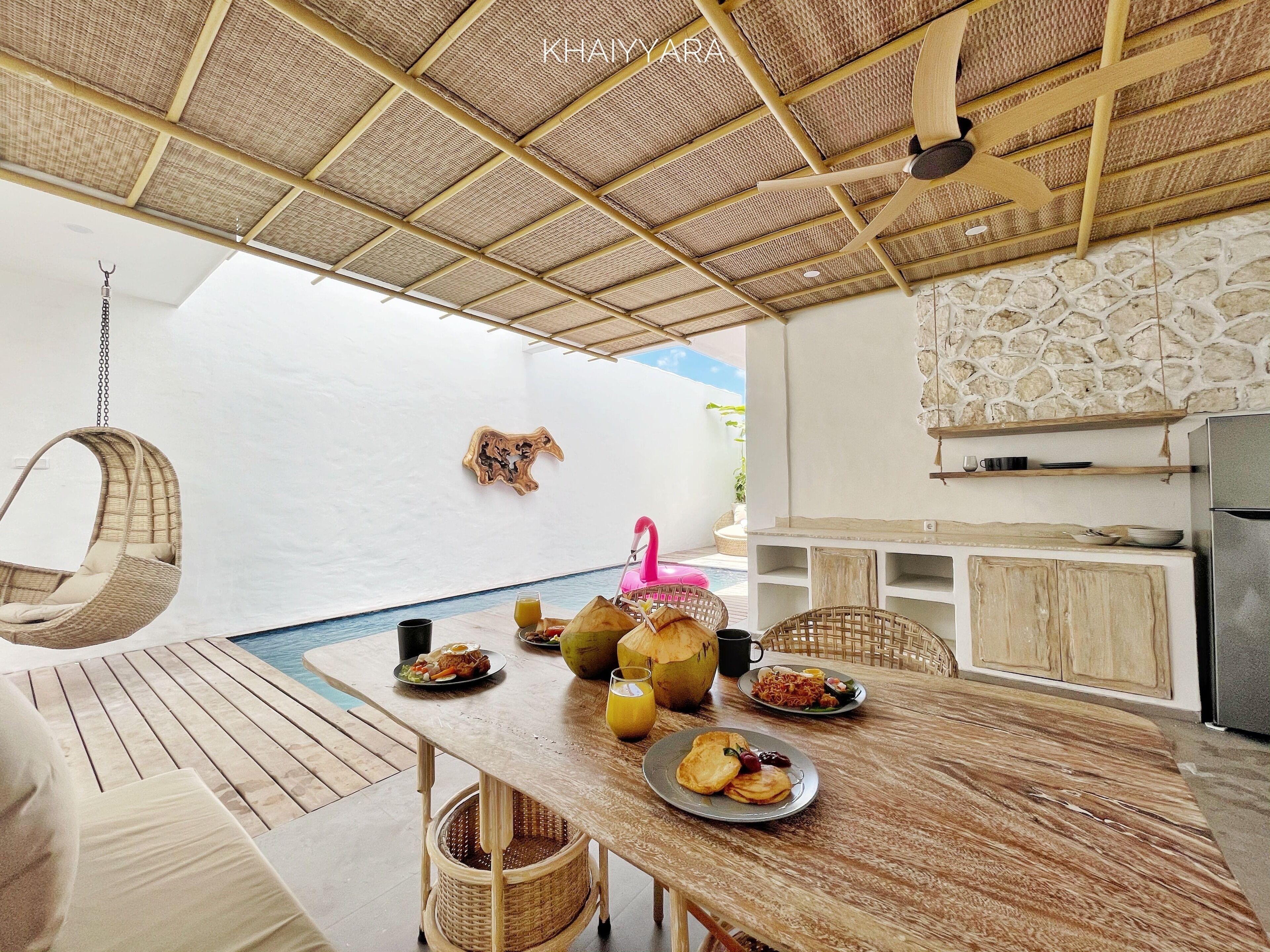 Comedor con piscina, muebles de madera y ventilador de techo.