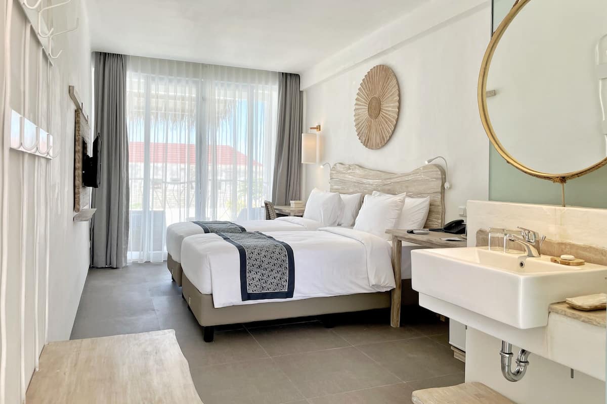 Una habitación de hotel con cama, mesita de noche y baño con lavabo y espejo.