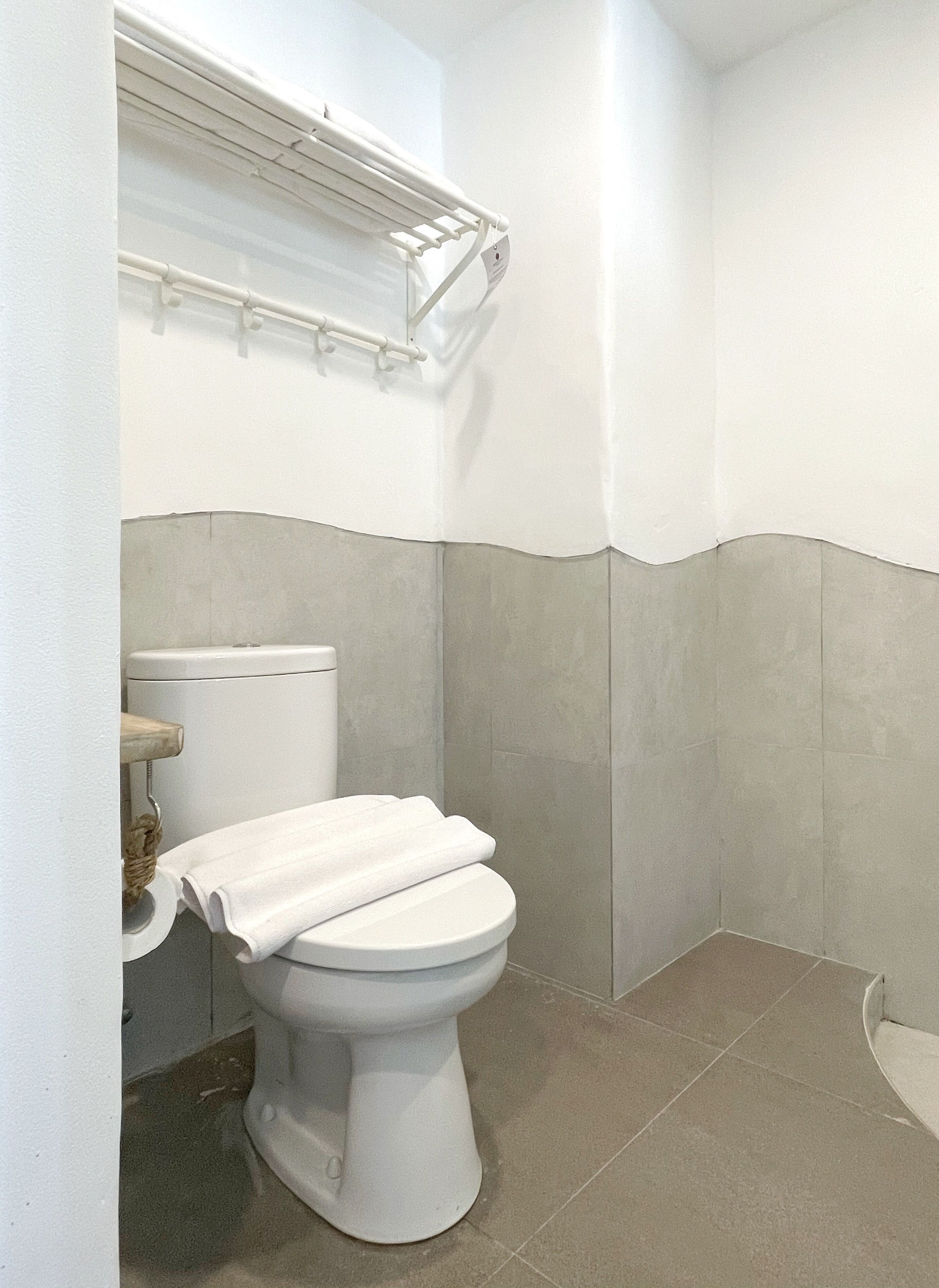 A small, clean bathroom with a toilet, a towel rack, and a shower area.