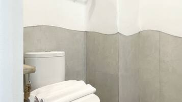 Ein kleines, sauberes Badezimmer mit Toilette, Handtuchhalter und Duschbereich.