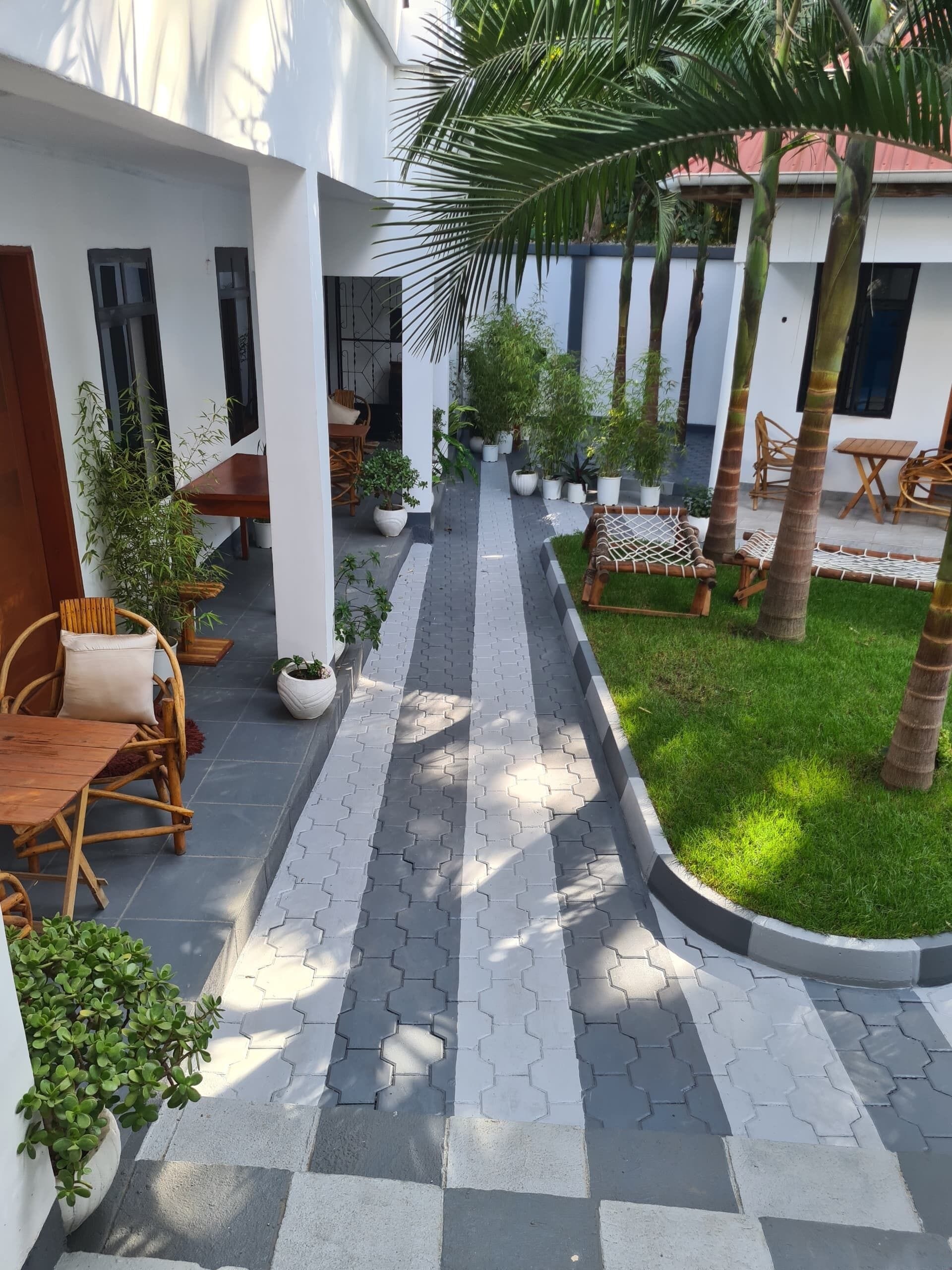 A courtyard with a paved walkway, outdoor seating, and potted plants.