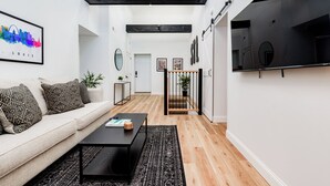 Ein modernes Wohnzimmer mit einer Couch, einem Couchtisch und einem an der Wand befestigten Fernseher.