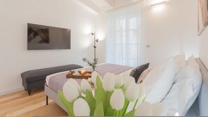 Une chambre moderne avec un lit, un banc et un téléviseur fixé au mur.