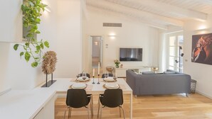 Un salon moderne comprenant un coin repas, un canapé gris et un téléviseur à écran plat.
