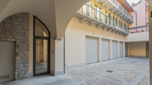 Une cour intérieure avec une arche en pierre, une porte vitrée et un sol carrelé.