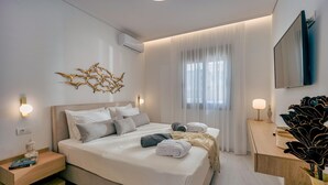 Ett modernt hotellrum med en stor säng, sängbord, en platt-TV och ett stort fönster med tunna, genomskinliga gardiner.