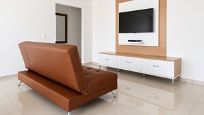 Ein modernes Wohnzimmer mit einem braunen Ledersofa, einer weißen Unterhaltungseinheit und einem flachbildfernseher an der Wand.
