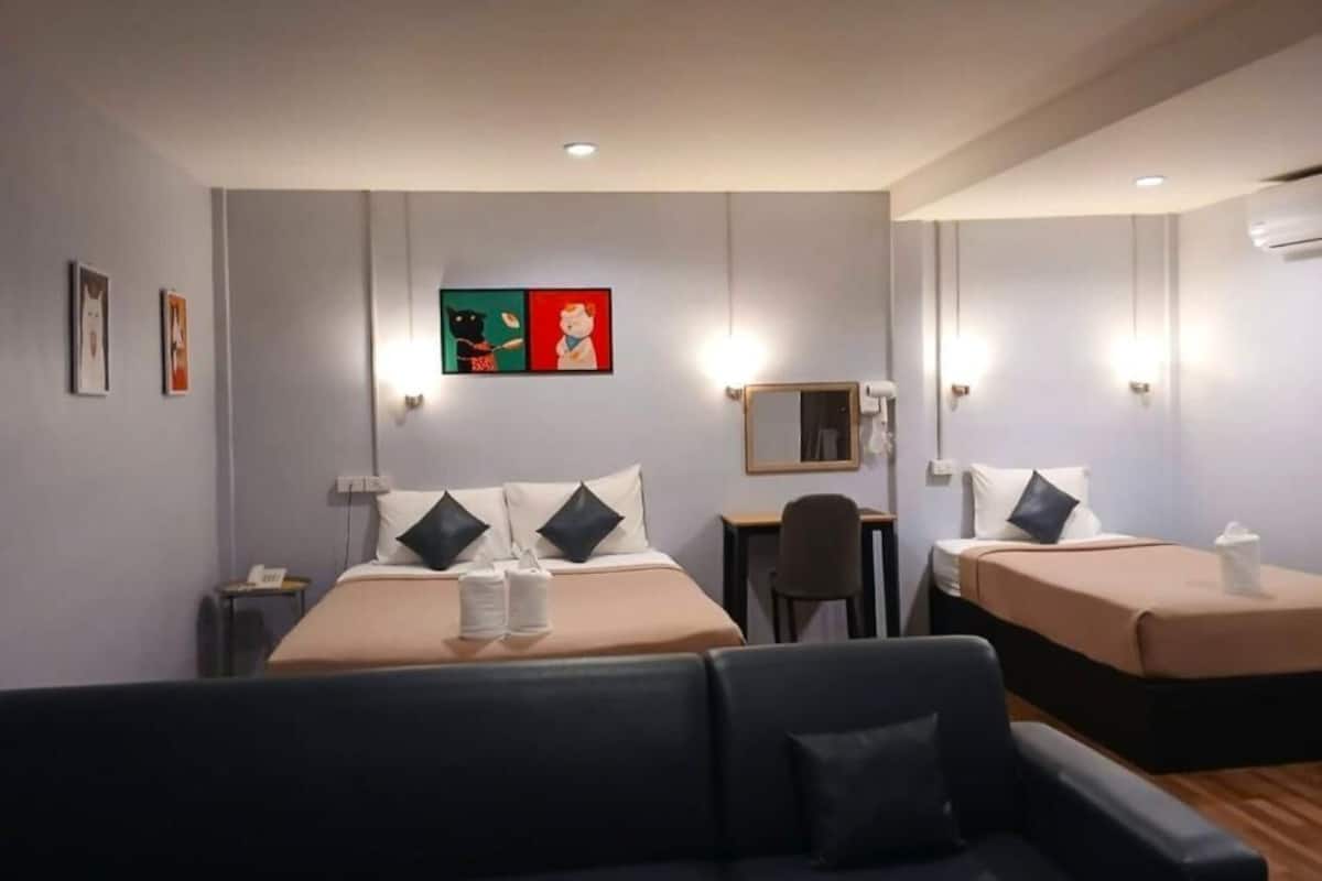 A hotel room with two beds, a desk, a chair, and a sofa.