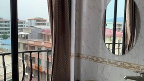 A bathroom with a marble sink, a round mirror, and a view of buildings through a window. - Shangxi Apartment (Zhaoqing)
