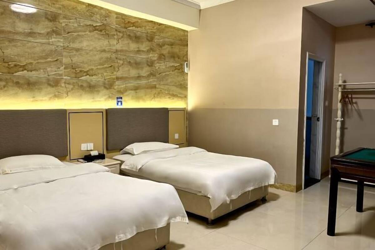 A hotel room with two beds, a pool table, and a stone wall.