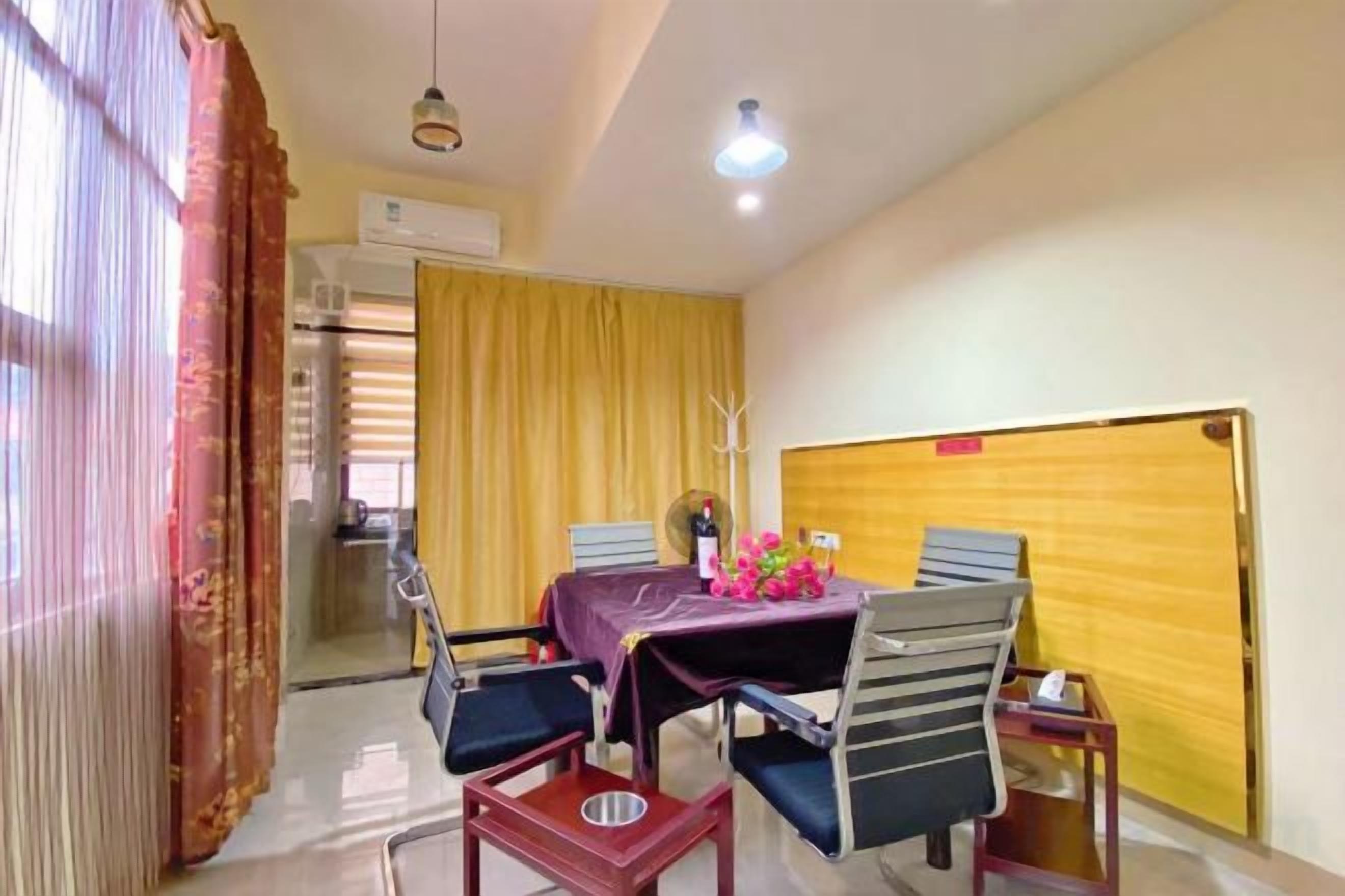 A dining area with a table, chairs, and a yellow curtain.