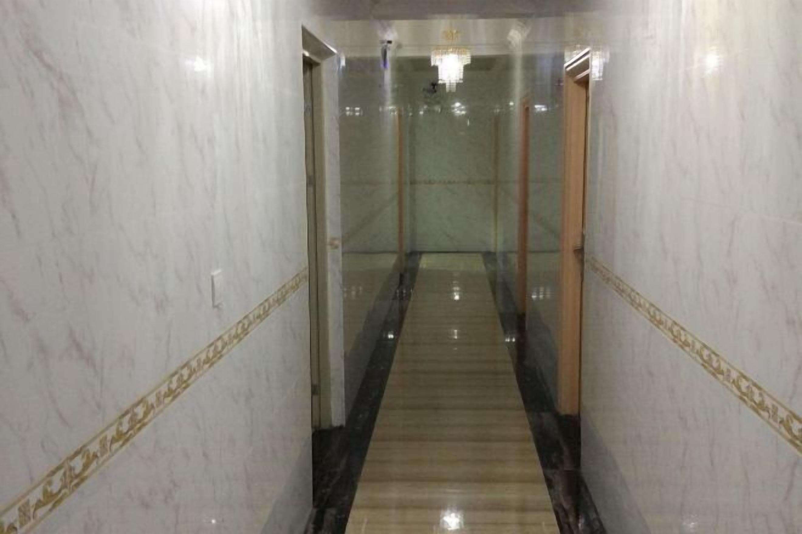 A marble hallway with a central carpeted walkway, glass doors, and a chandelier.
